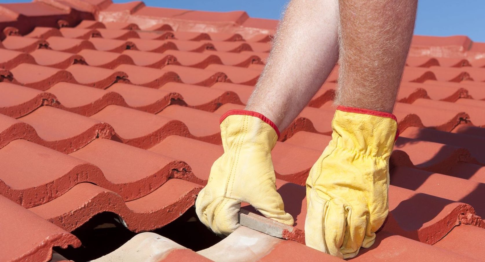 roofer wearing gloves replacing roof tiles